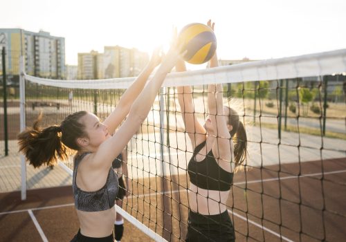 Ein Volleyballnetz, bei dem 2 Frauen gegeneinander spielen.